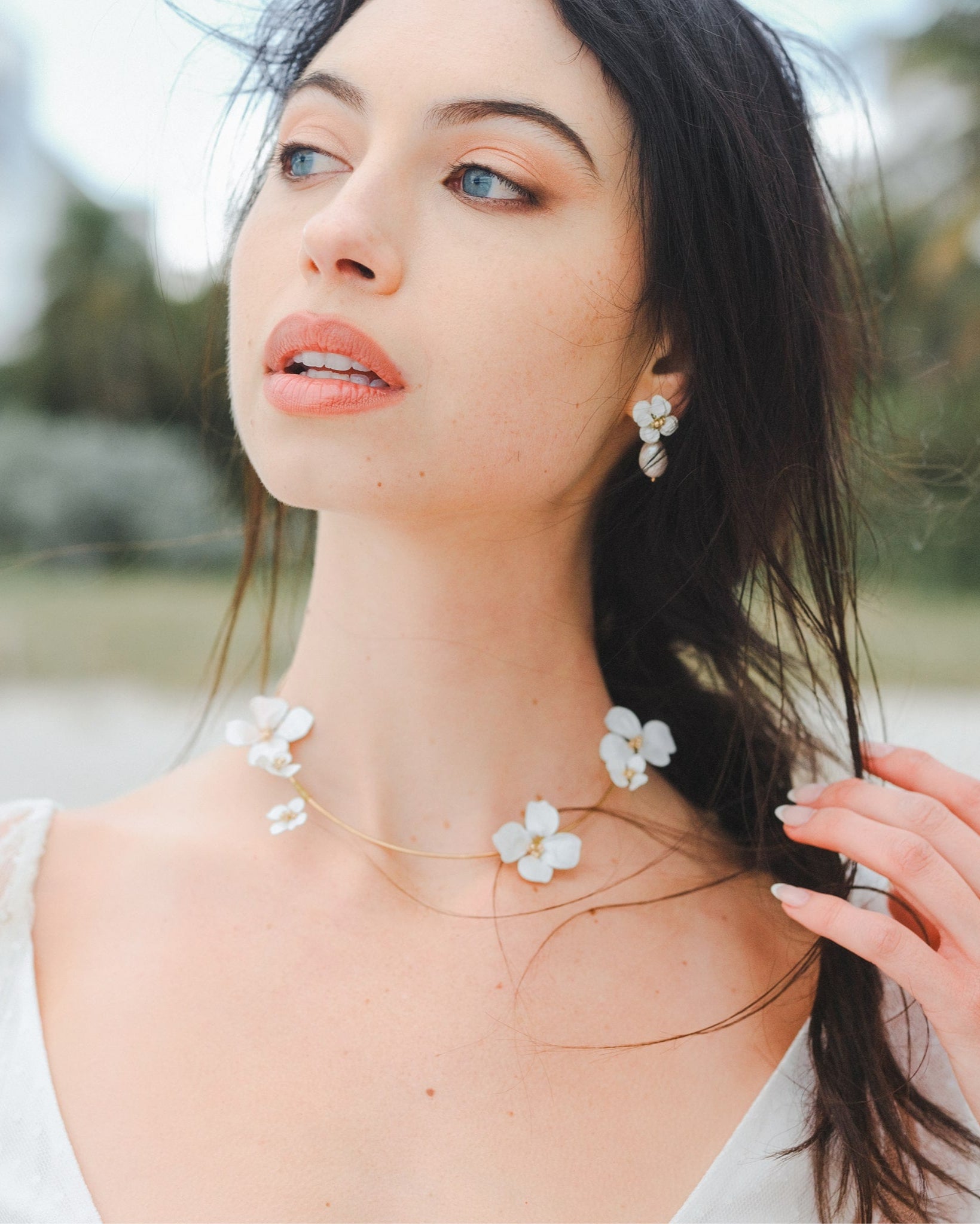 Parure elegante da sposa con collana e orecchini decorati con fiori bianchi, ideale per un look armonioso e raffinato.