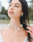 Parure elegante da sposa con collana e orecchini decorati con fiori bianchi, ideale per un look armonioso e raffinato.