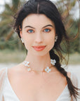 Set di gioielli da sposa con collana e orecchini decorati con fiori bianchi, eleganza e raffinatezza per il giorno del matrimonio.
