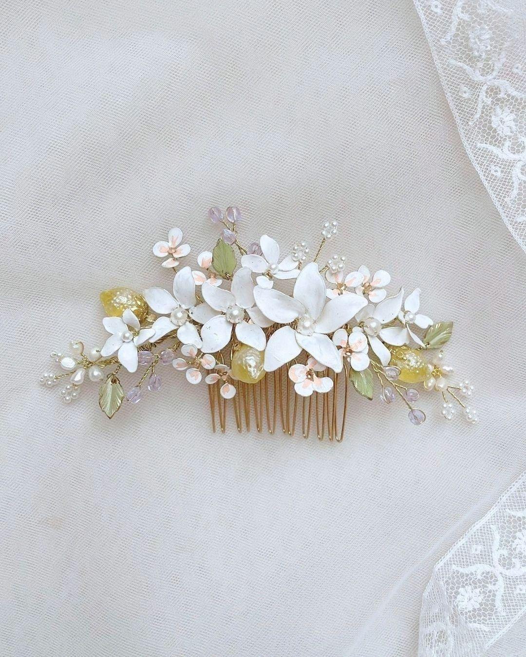 Pettinino appoggiato su tessuto chiaro, con fiori bianchi, dettagli gialli e base a pettine dorata