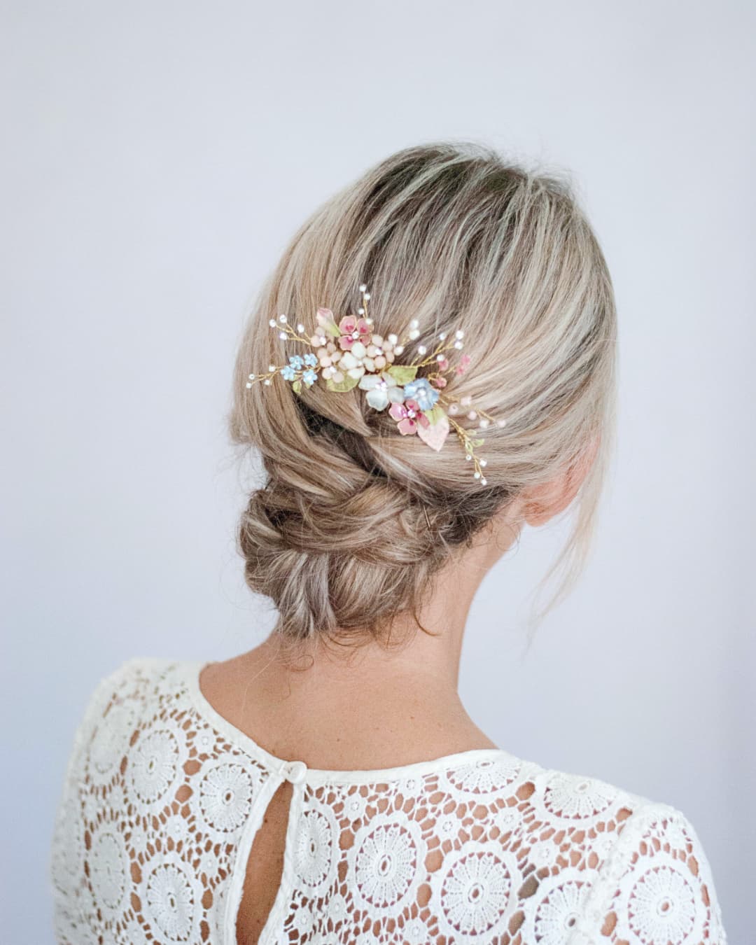 Dettaglio artigianale del pettinino Millefiori con fiori smaltati e foglie dorate per acconciatura nuziale.