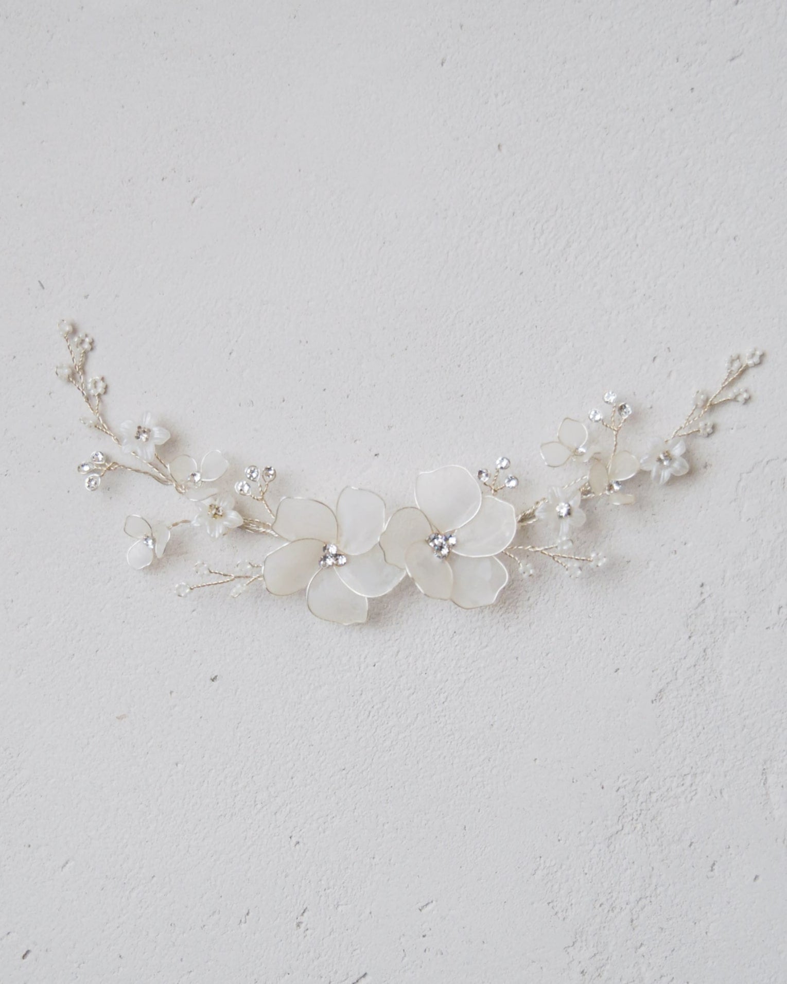 Accessorio per capelli con fiori satinati e cristalli, ideale per cerimonie romantiche.