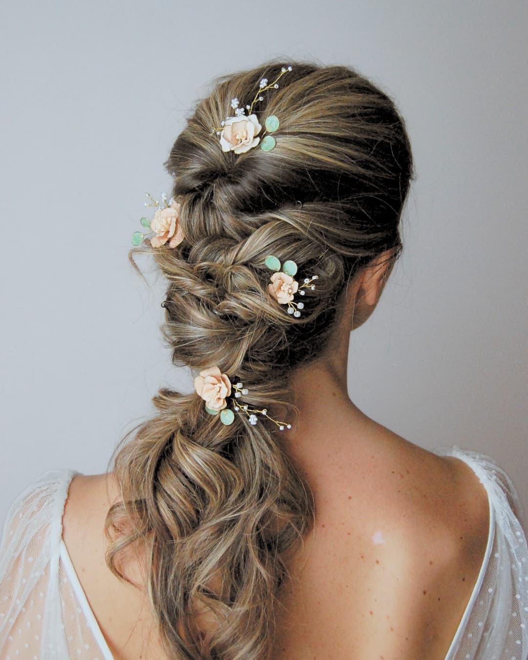 Styling sposa con set di forcine floreali rosa pesca e eucalipto per un look botanico d'eccellenza.