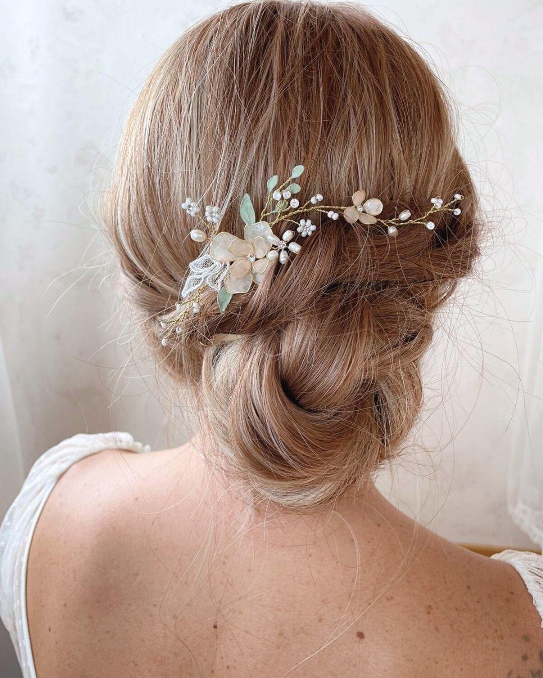 Forcina modellabile Roselle applicata su un'acconciatura sposa raccolta, effetto botanico tra i capelli con riflessi pesca.