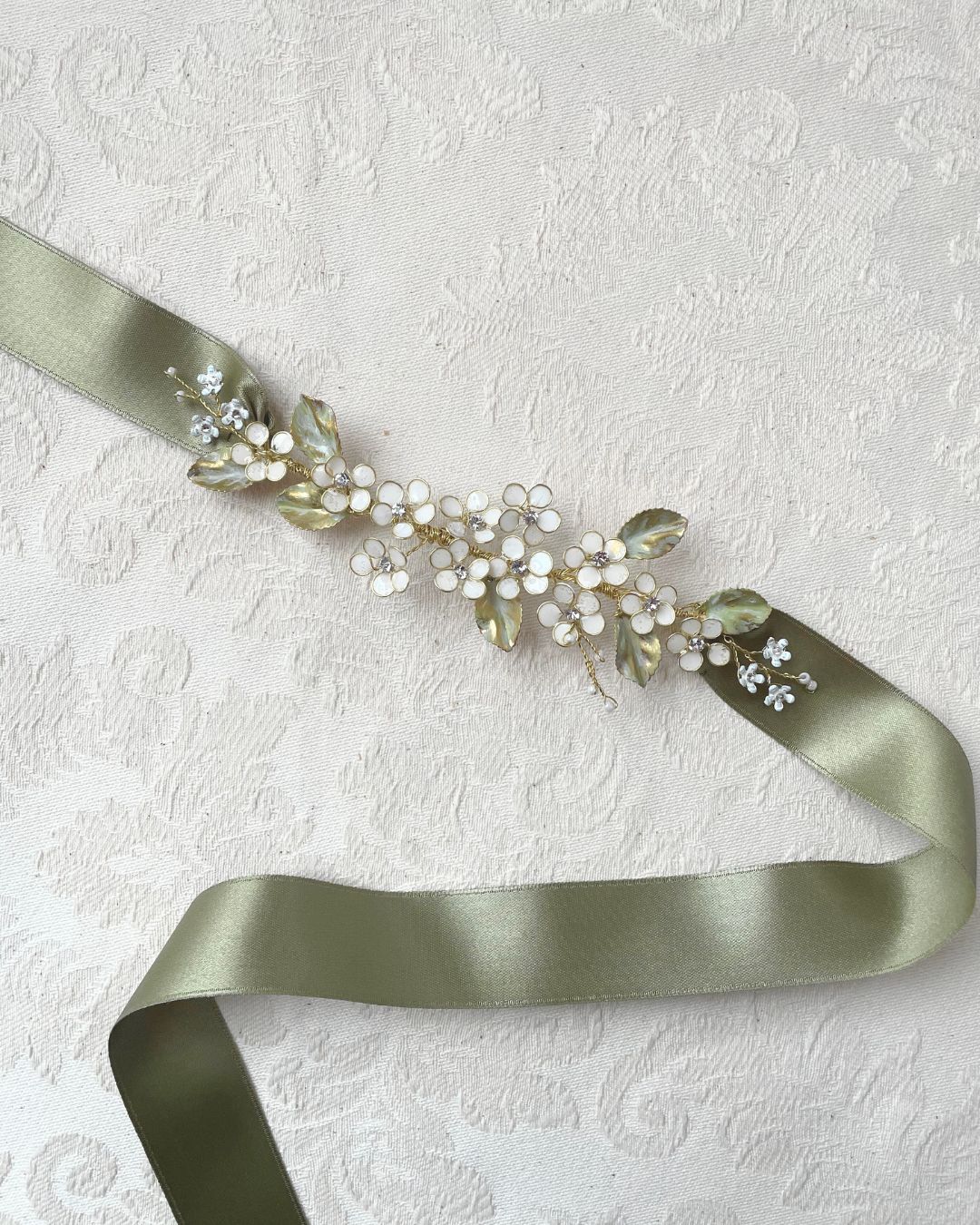 Cintura da sposa personalizzata Elibre con fiori bianchi e foglie verdi su nastro in raso verde salvia