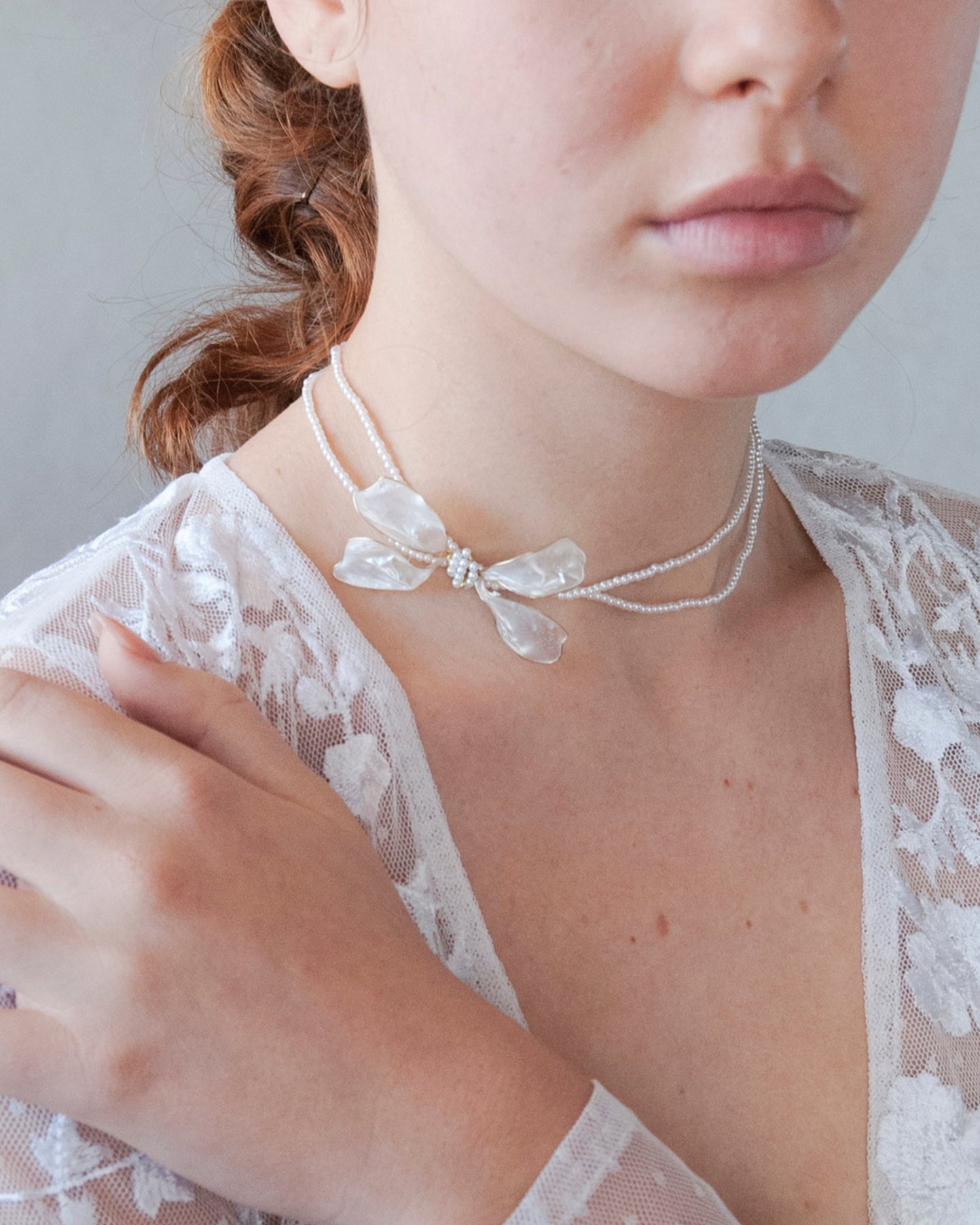 Accessorio elegante: collana di perline con fiocco laterale per cerimonie chic.