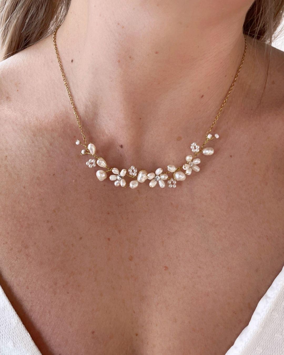 Primo piano della collana Marguerite indossata su abito da sposa, evidenziando la luminosità delle perle sul décolleté.