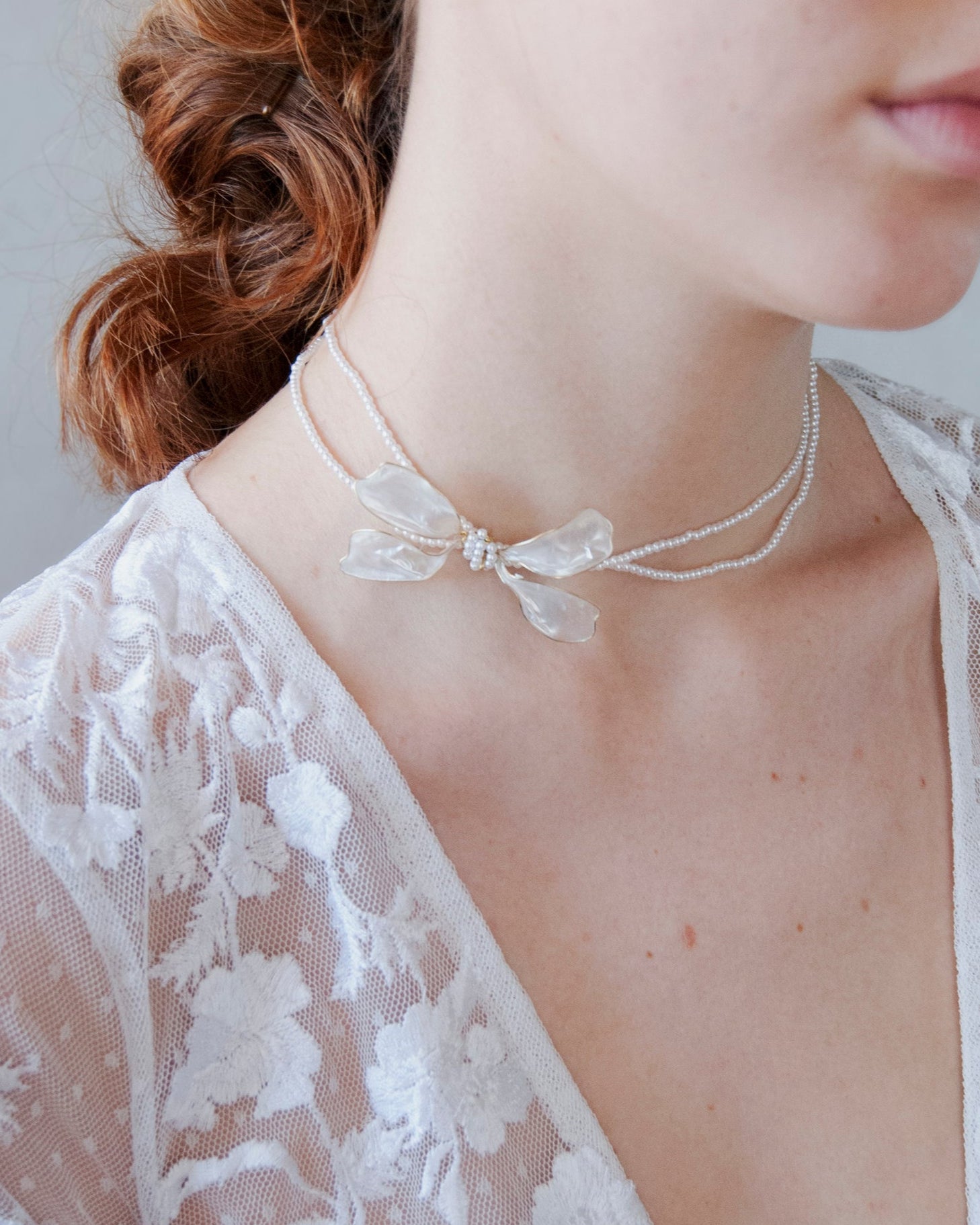 Collana di perline con fiocco laterale, perfetta per spose eleganti.