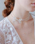 Collana di perline con fiocco laterale, perfetta per spose eleganti.