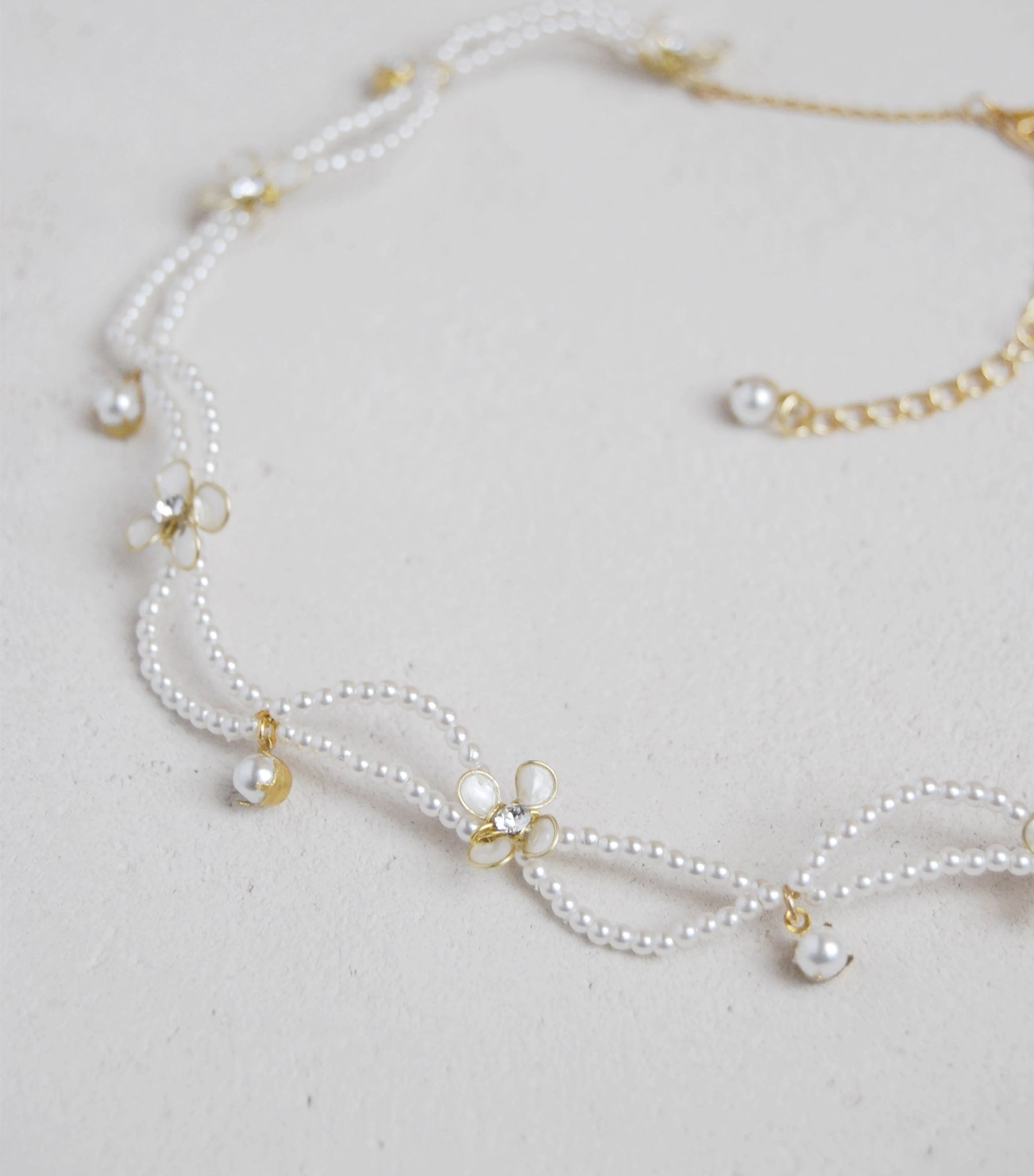 Elegante collana girocollo con motivo intrecciato, perle e fiorellini madreperlati per un look nuziale sofisticato.