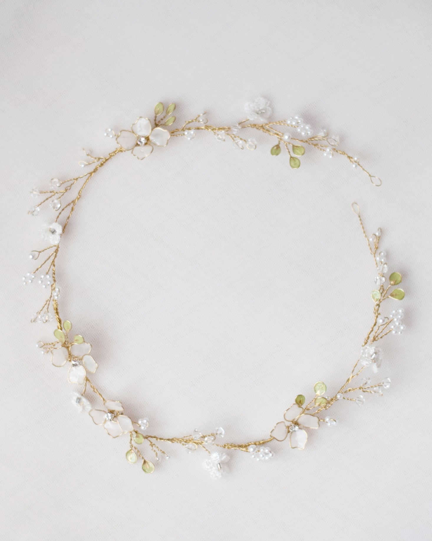 Coroncina da sposa Floralis con fiori bianchi in pizzo e rametti verdi, modellabile e romantica, perfetta per un look boho chic e versatile.