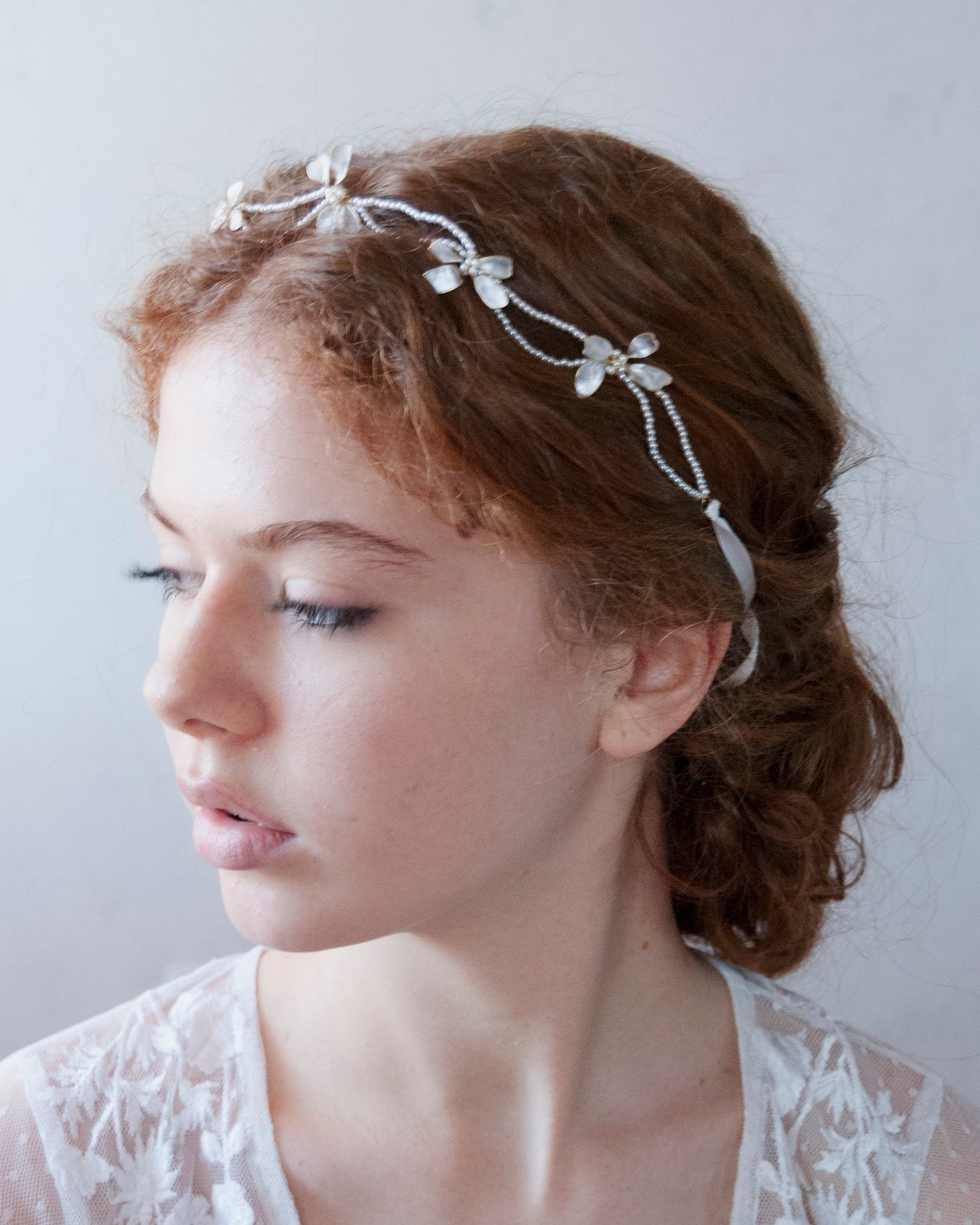 Coroncina floreale con perline e fiocchi madreperlati, per un look romantico.