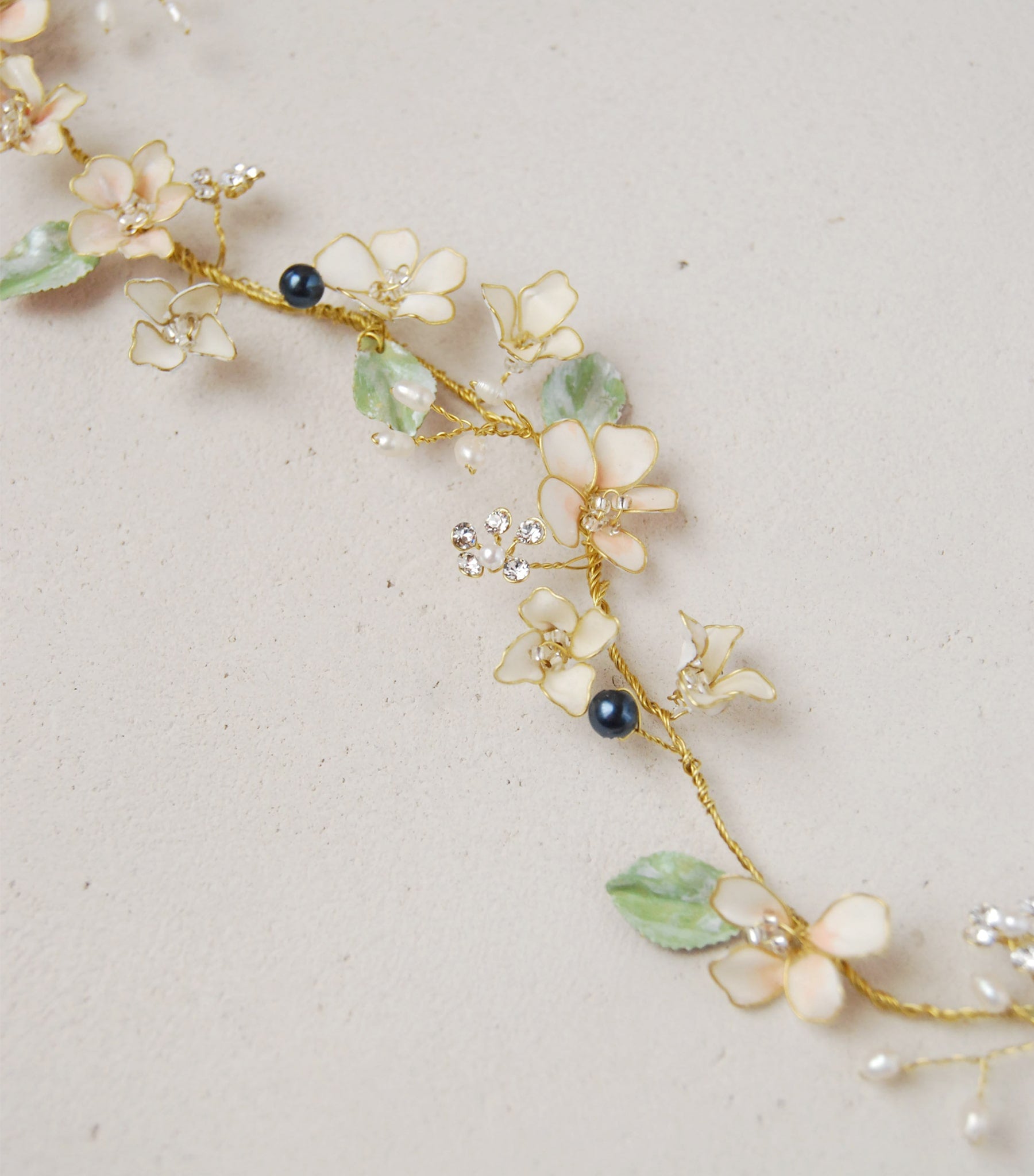 Coroncina con perle blu e fiori rosa, accessorio elegante per un'acconciatura da sposa sofisticata.