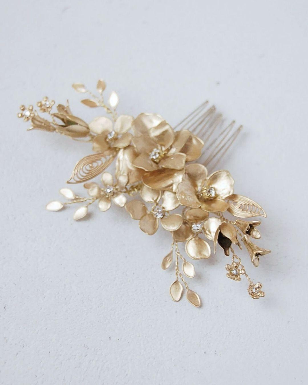 Primo piano dei fiori dorati artigianali e dei cristalli del pettinino d'alta gamma Aurum.