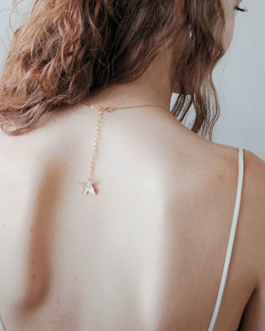 Dettaglio unico della collana Lieve: un piccolo fiore coordinato che cade elegantemente sulla schiena nuda.