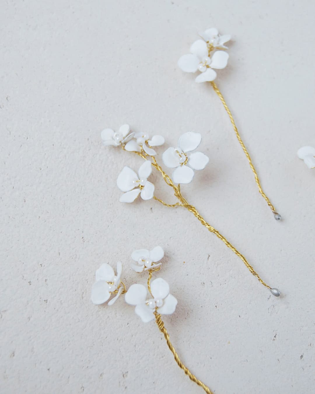 Particolare dei fiori bianchi effetto seta modellati a mano con perle per accessorio capelli sposa.
