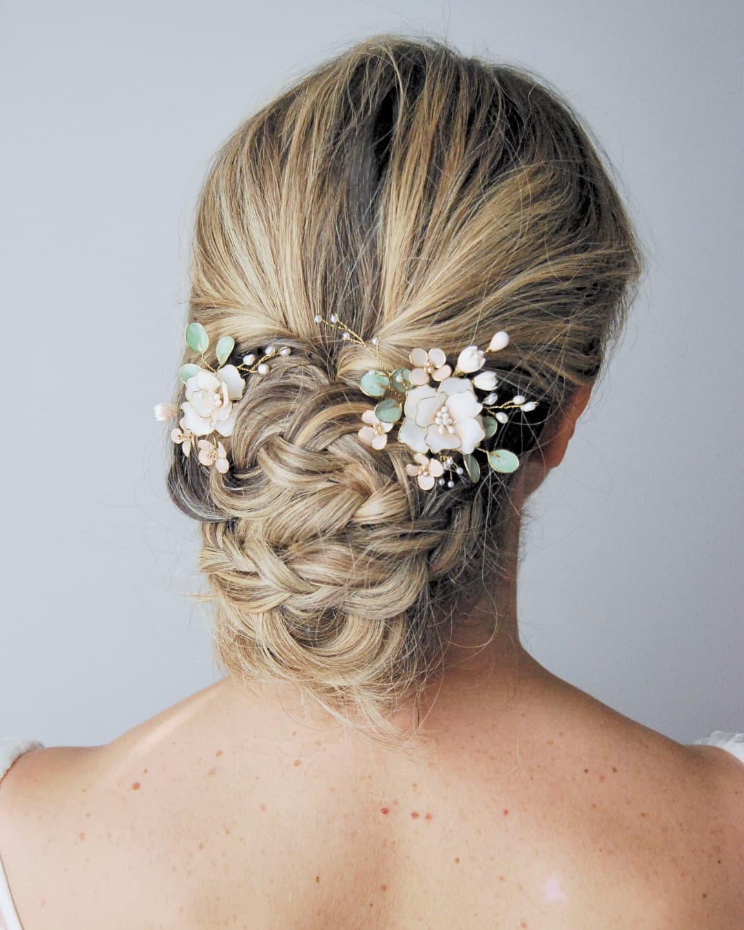 Primo piano del design floreale delle forcine Rosaclara con dettagli in perle e foglie verde salvia.