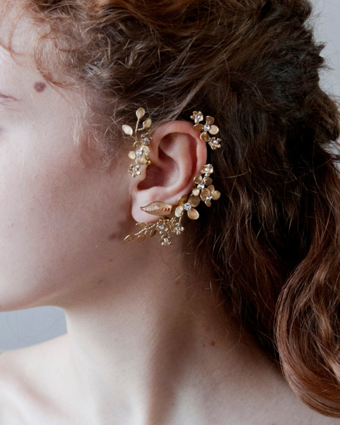 Ear cuff elegante dorato con motivi floreali, ideale per cerimonie speciali.