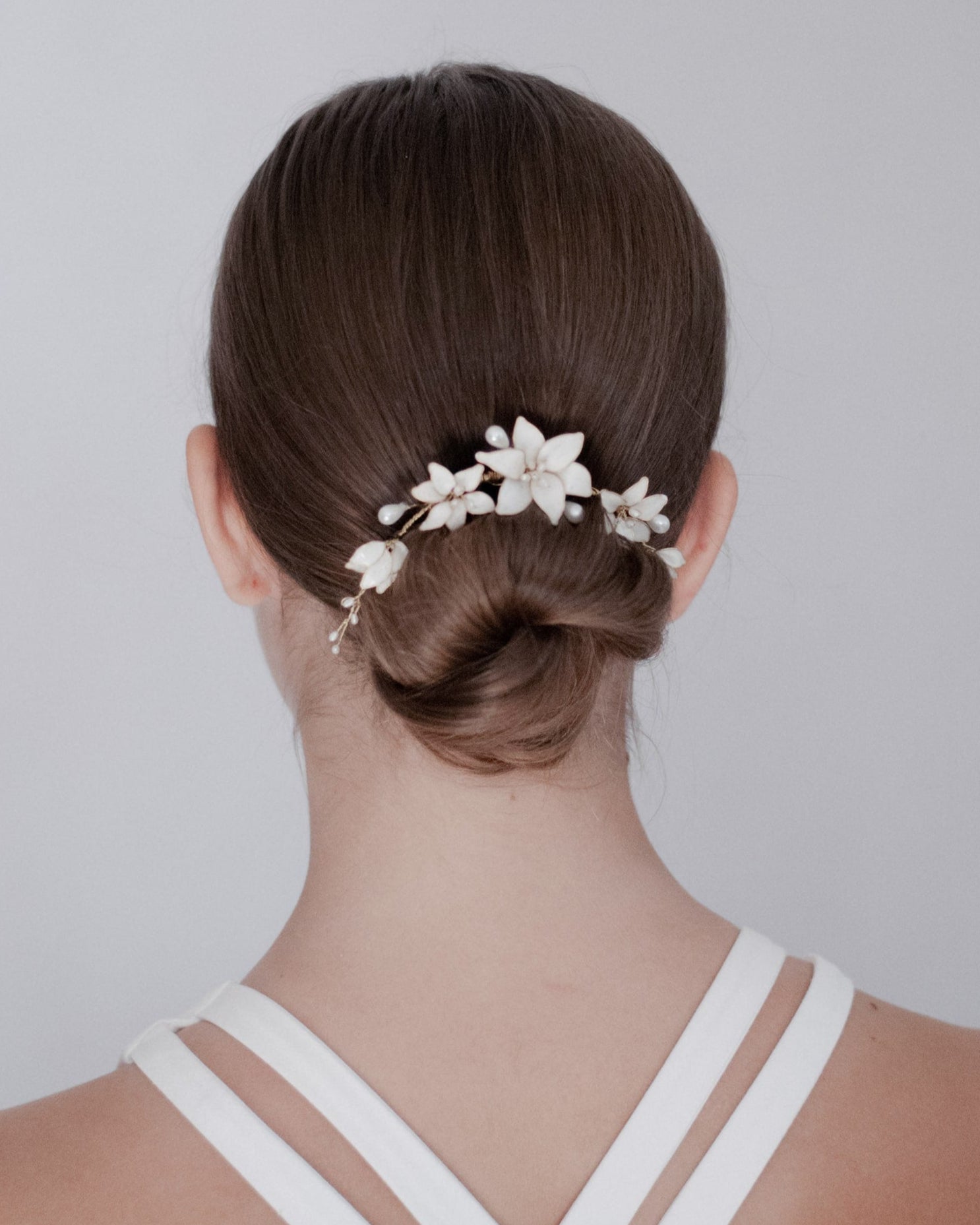 Fermaglio minimal chic con fiori bianchi, perfetto per spose dal gusto contemporaneo.