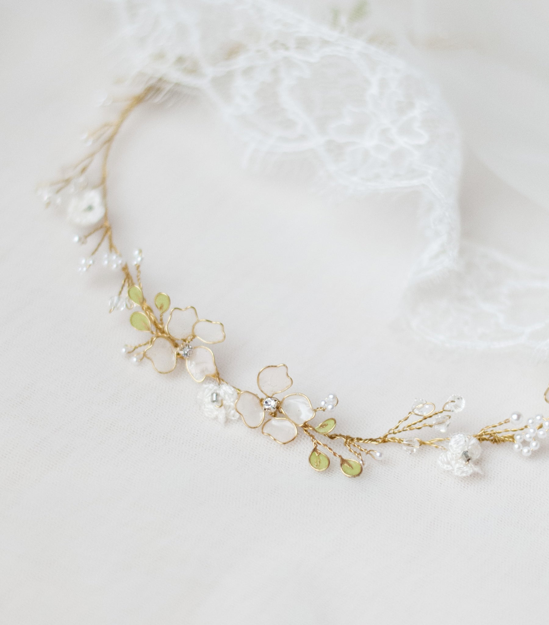 Coroncina Floralis da sposa con fiori bianchi in pizzo e rametti verdi, romantica e boho chic, modellabile e versatile per raccolti o capelli sciolti.