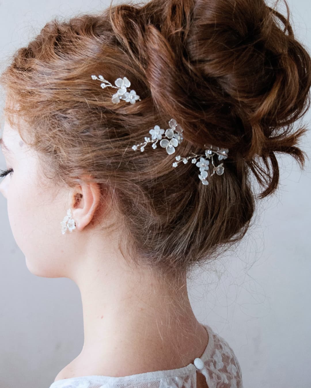 Set di 3 forcine Frostalia applicate su acconciatura raccolta da sposa, dettaglio fiori bianchi tra i capelli