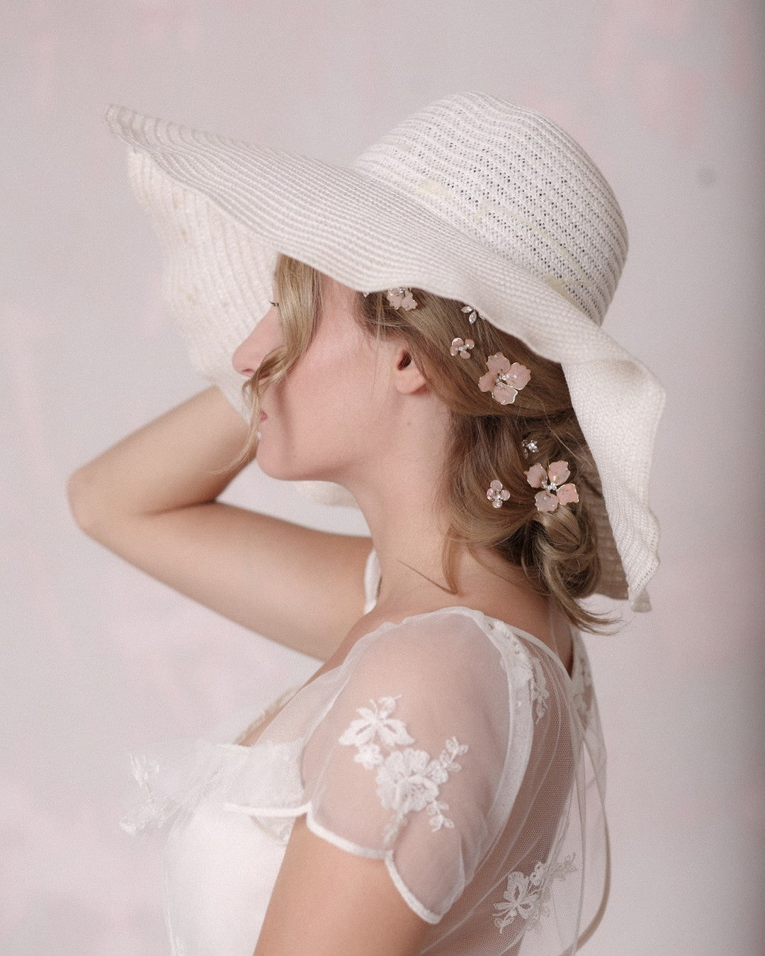 Forcine da sposa floreali rosa Elibre indossate con cappello di paglia bianco, look nuziale boho estivo