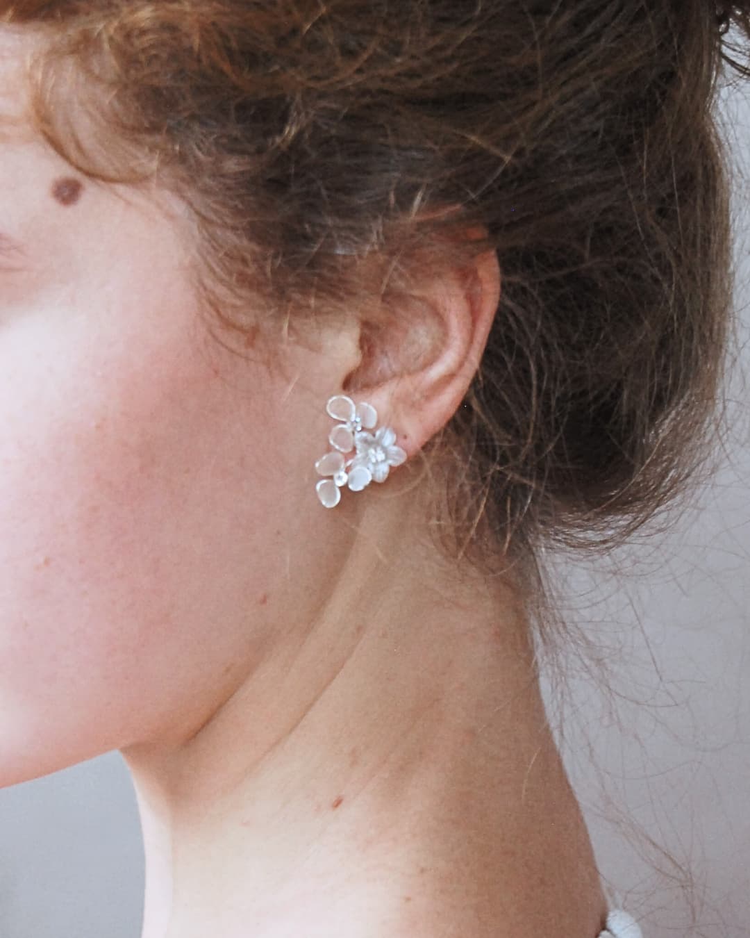 Orecchini con composizione scultorea di fiorellini bianchi traslucidi per un bridal look poetico.