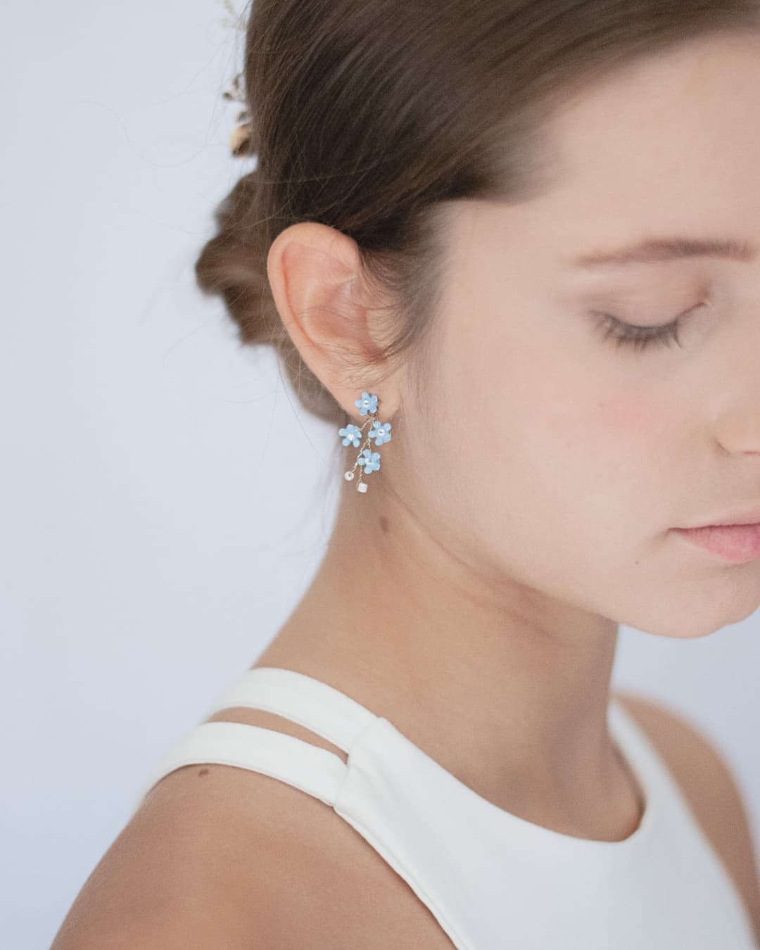 Dettaglio di orecchini floreali azzurri, l'accessorio perfetto per inserire il "qualcosa di blu" in un bridal look d'élite.