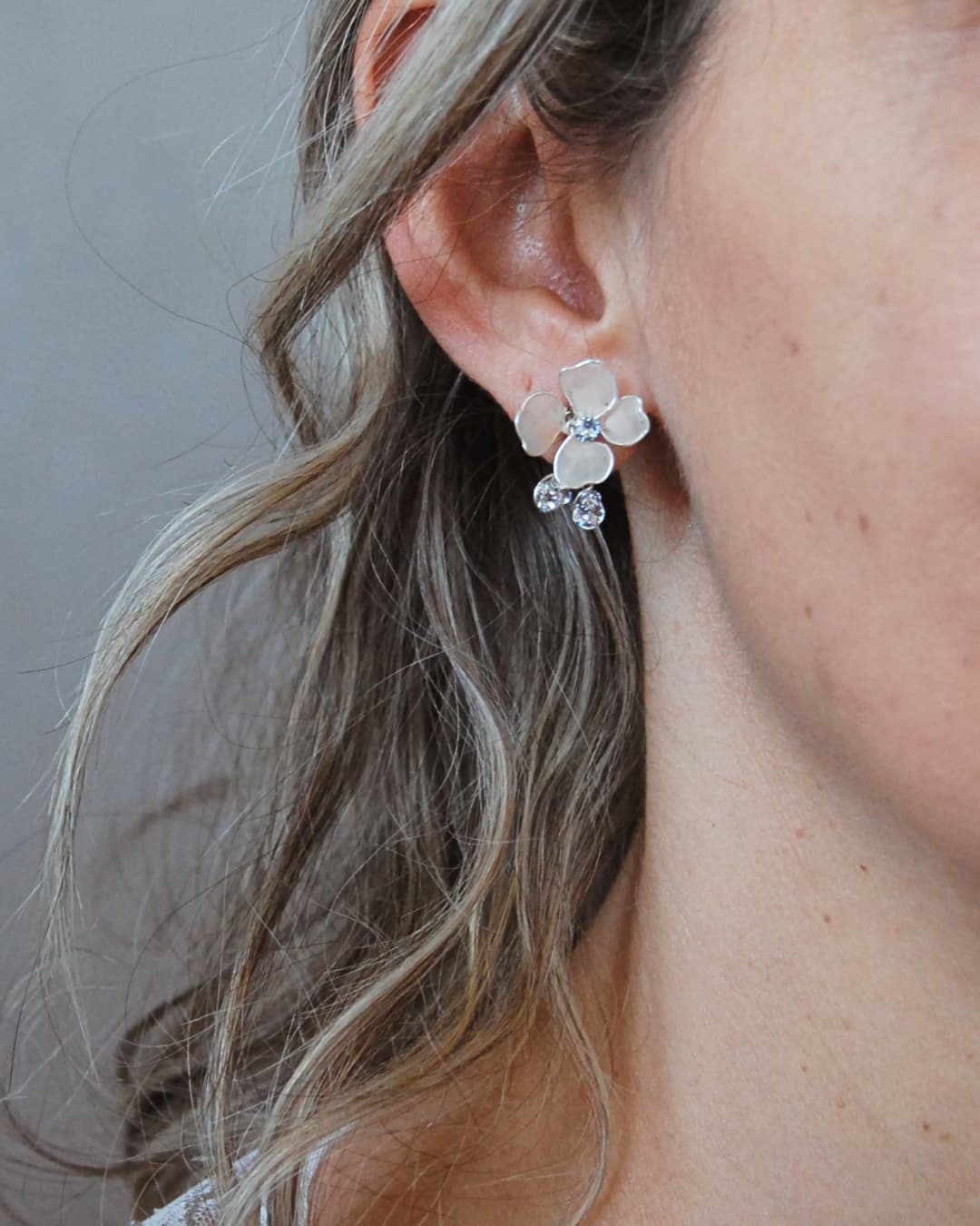 Dettaglio dei petali rosa satinati degli orecchini artigianali Etherea per sposa.