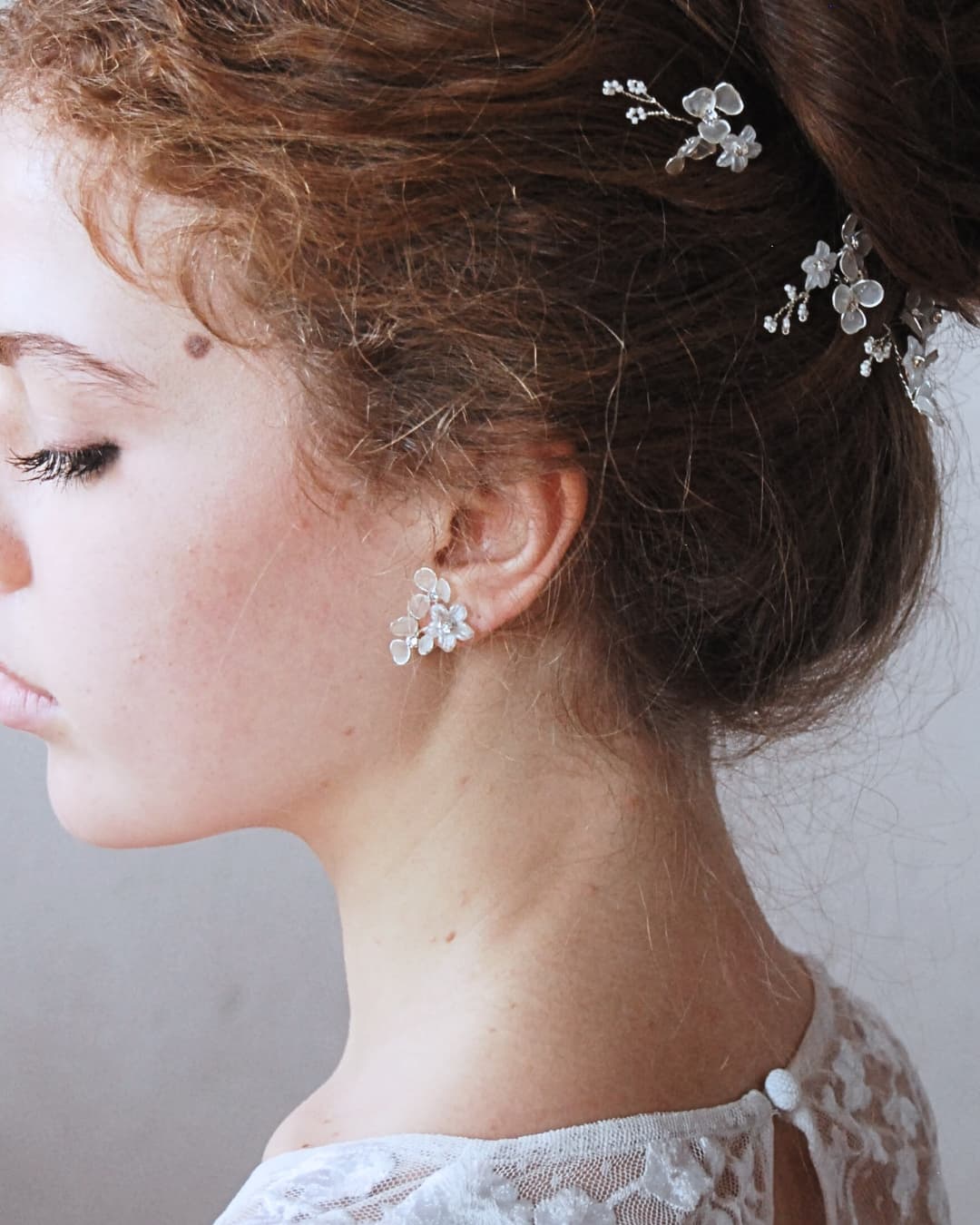 Dettaglio di orecchini floreali con petali traslucidi effetto brina e piccoli cristalli luminosi.