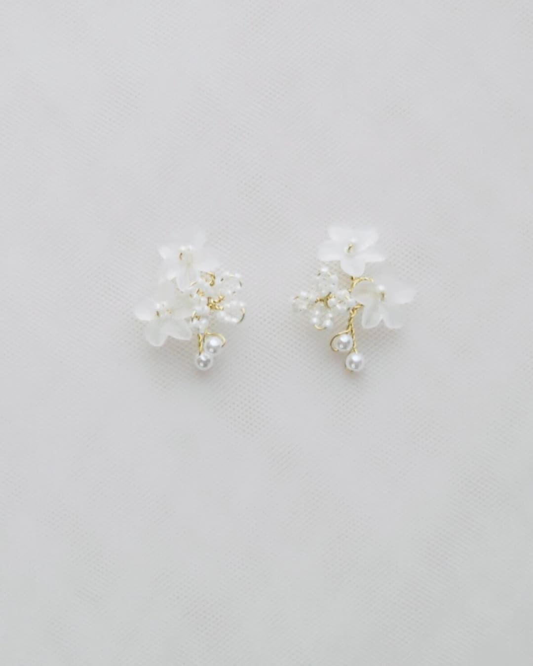 Primo piano degli orecchini Frangipane che mostra la texture dei petali e l'intreccio di perline fatto a mano in finitura oro.