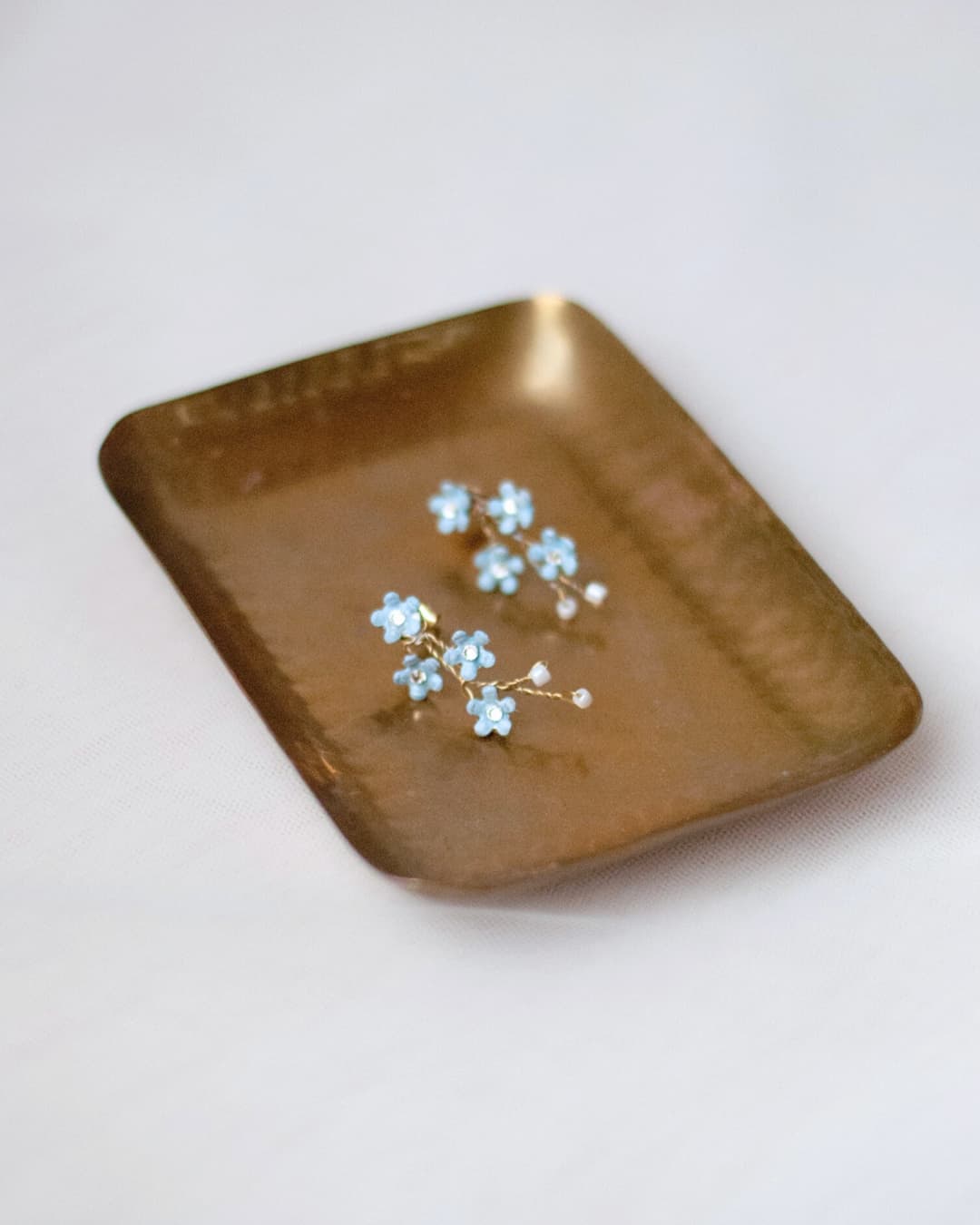 Orecchini artigianali Non ti Scordar di Me Elibre con ramage di fiori azzurro pastello e cristalli luminosi.