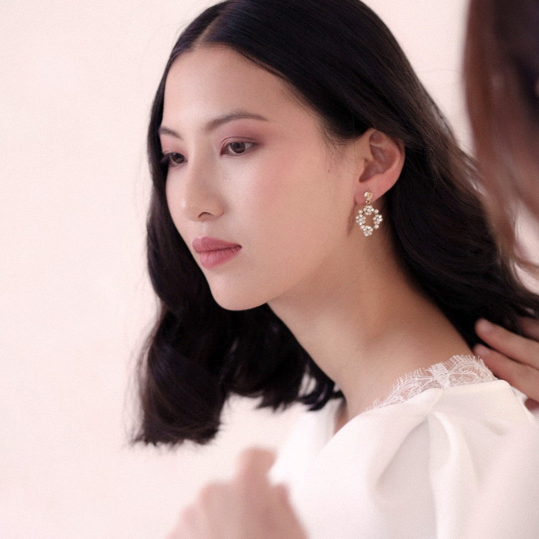 Orecchini pendenti da sposa con cristalli, indossati per un look luminoso ed elegante.