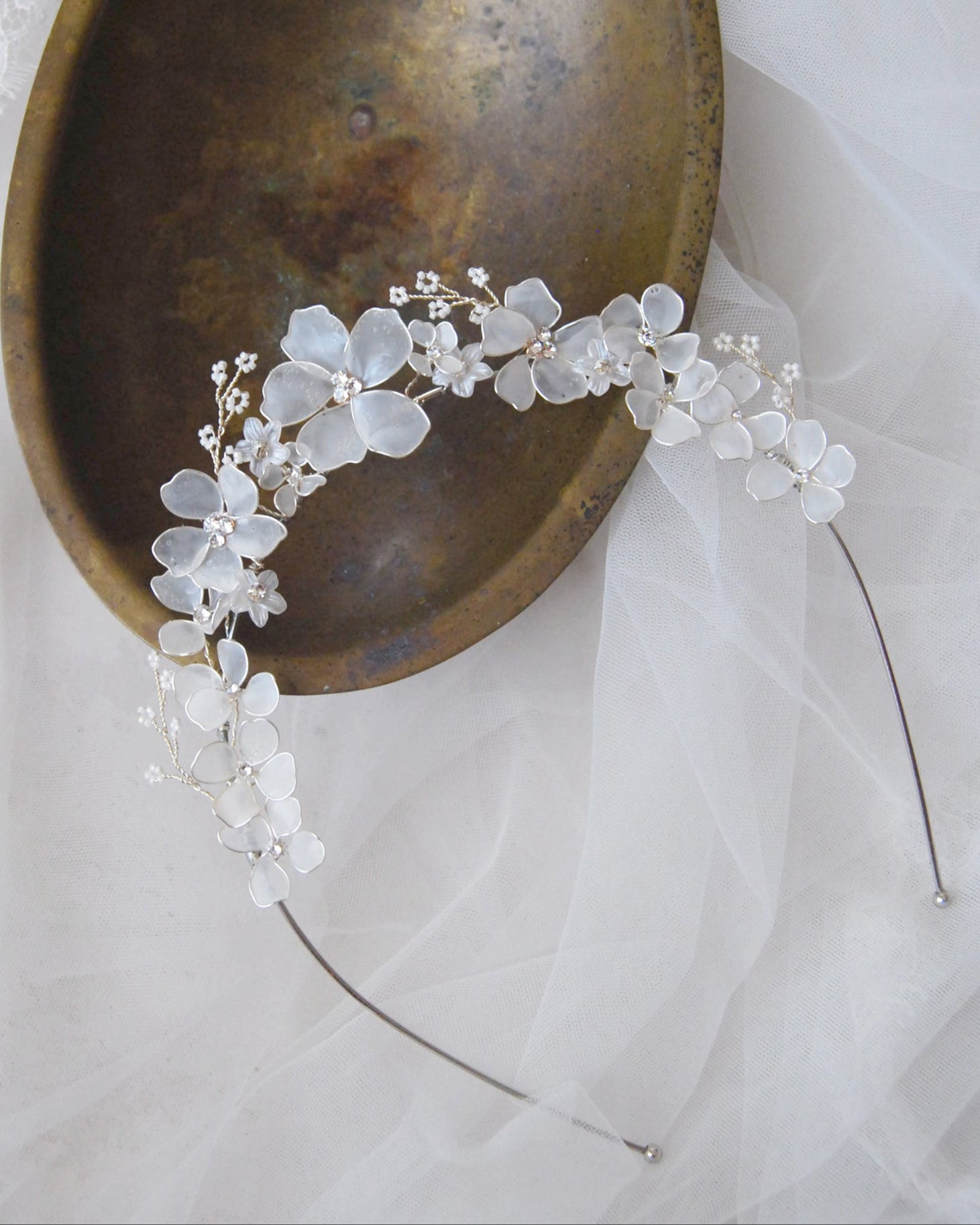 Tiara elegante con fiori bianchi satinati, perfetta per completare un'acconciatura da sposa romantica.