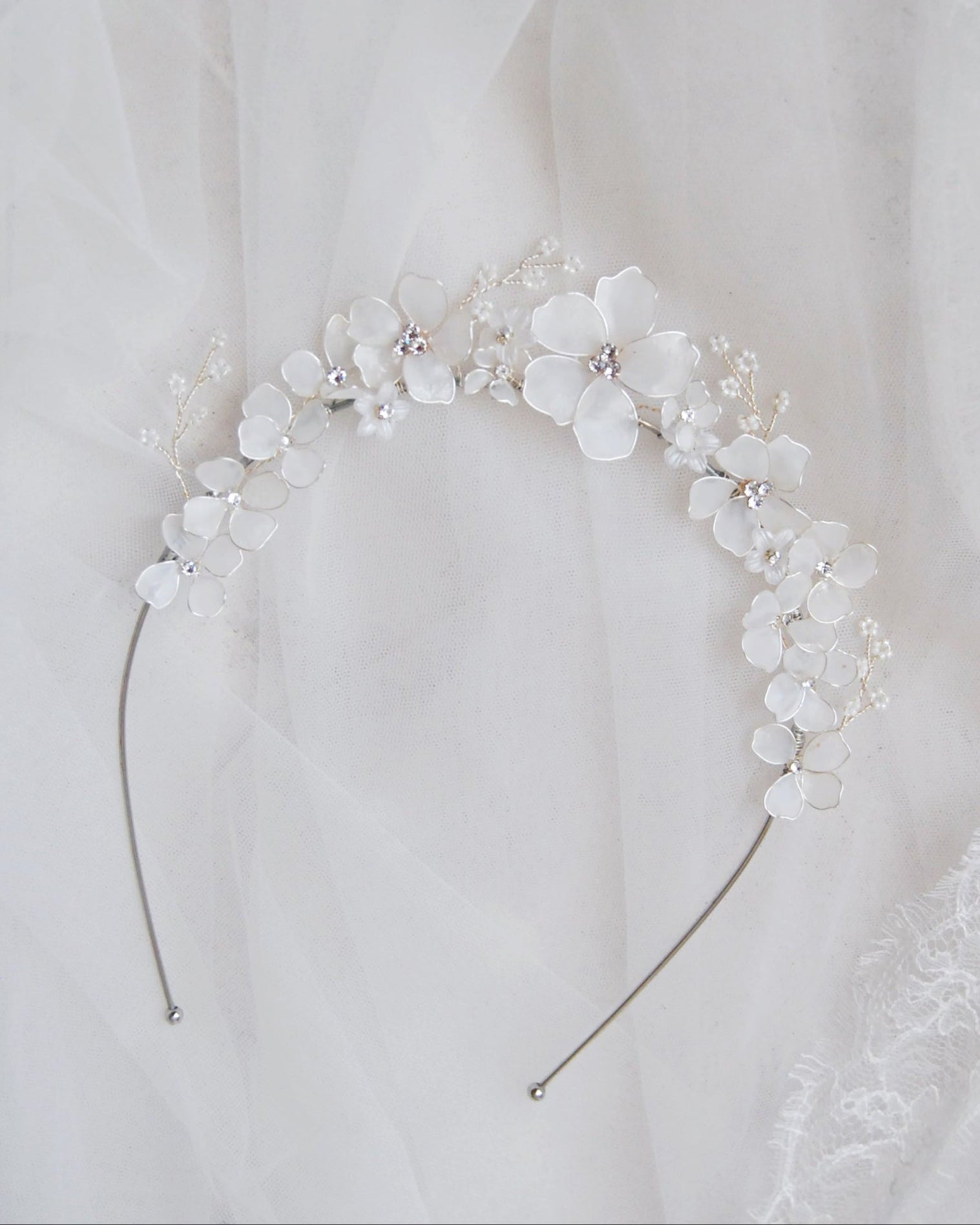 Tiara floreale con dettagli satinati bianchi, un accessorio chic per spose eleganti.