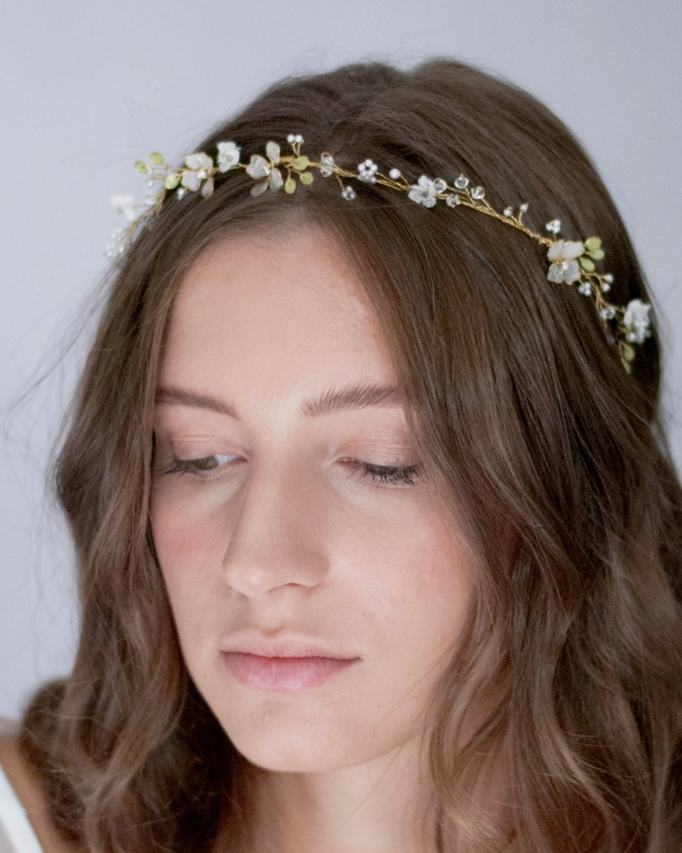 Coroncina eterea con fiorellini in pizzo e dettagli di foglie, per un look naturale.