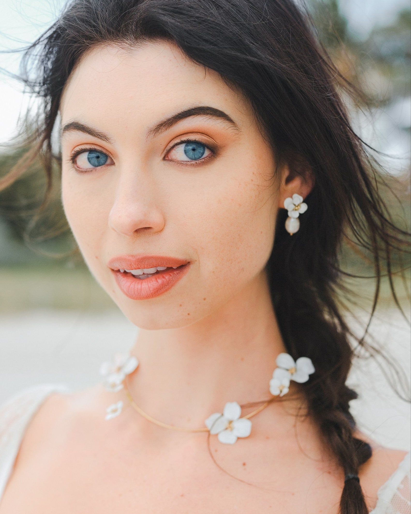 Elegante parure da sposa con collana e orecchini decorati con fiori bianchi, per un look sofisticato e armonioso.
