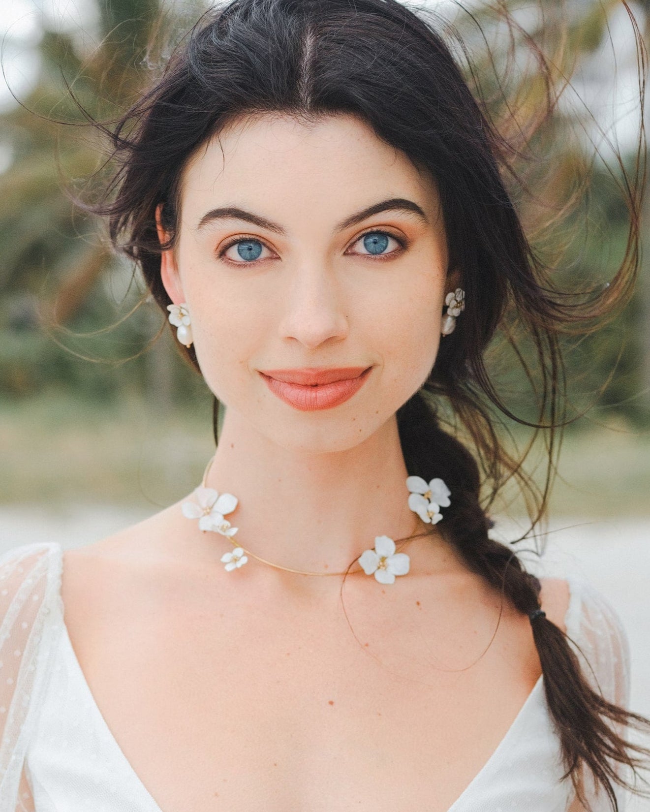 Set di gioielli da sposa con collana e orecchini decorati con fiori bianchi, eleganza e raffinatezza per il giorno del matrimonio.
