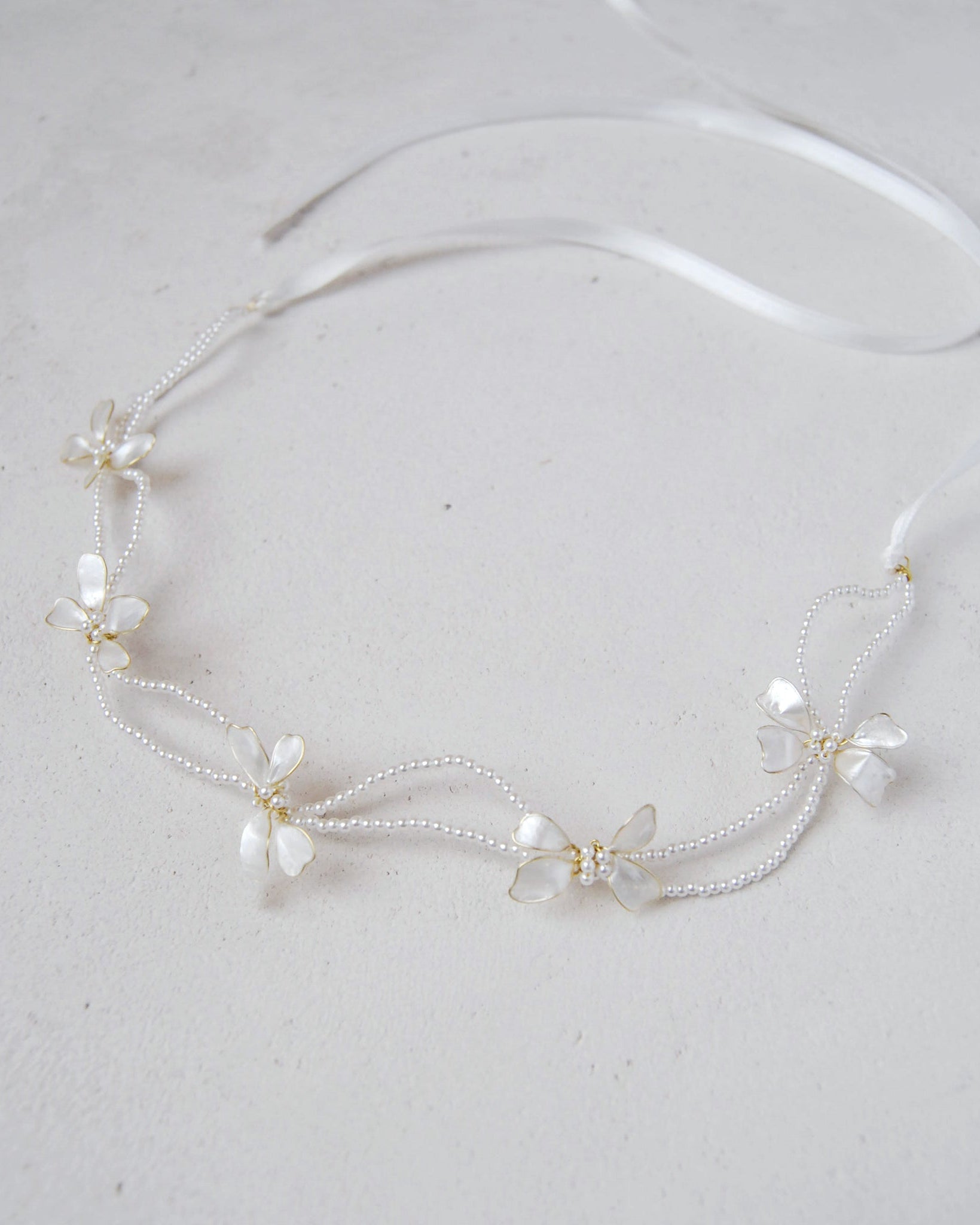 Accessorio per capelli da sposa: coroncina con perline e fiocchi madreperlati.