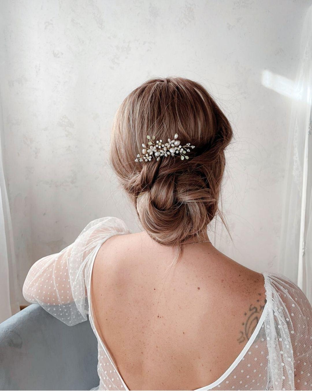 Esempio di acconciatura sposa con chignon morbido decorato dal pettinino Marguerite Lux a ramage dorato.