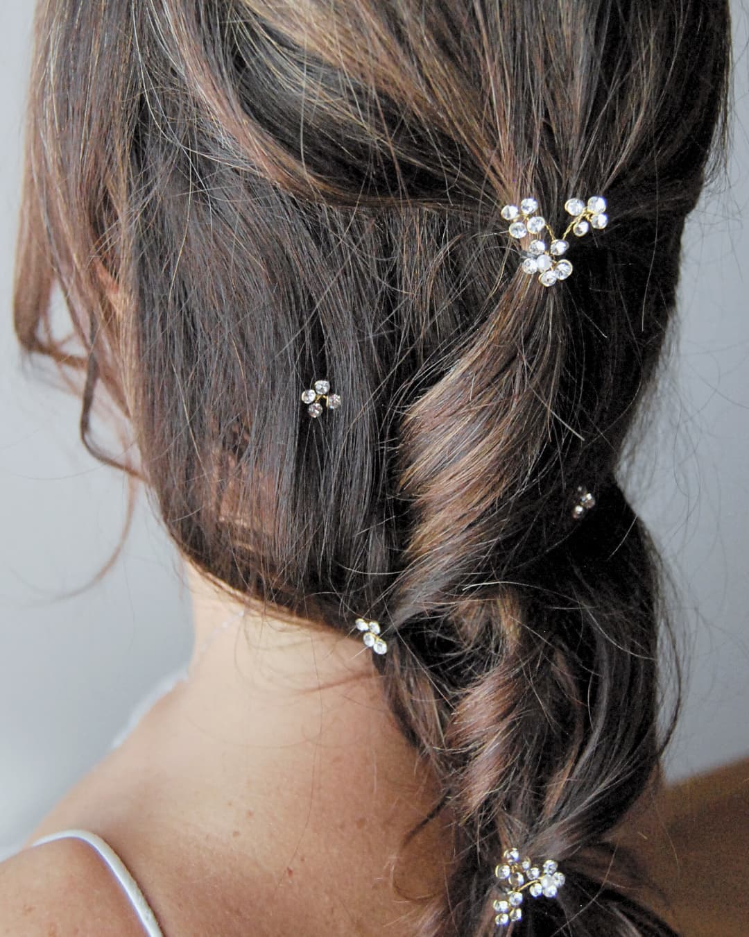 Acconciatura sposa con treccia morbida illuminata da piccoli fiorellini di cristallo Swarovski®.