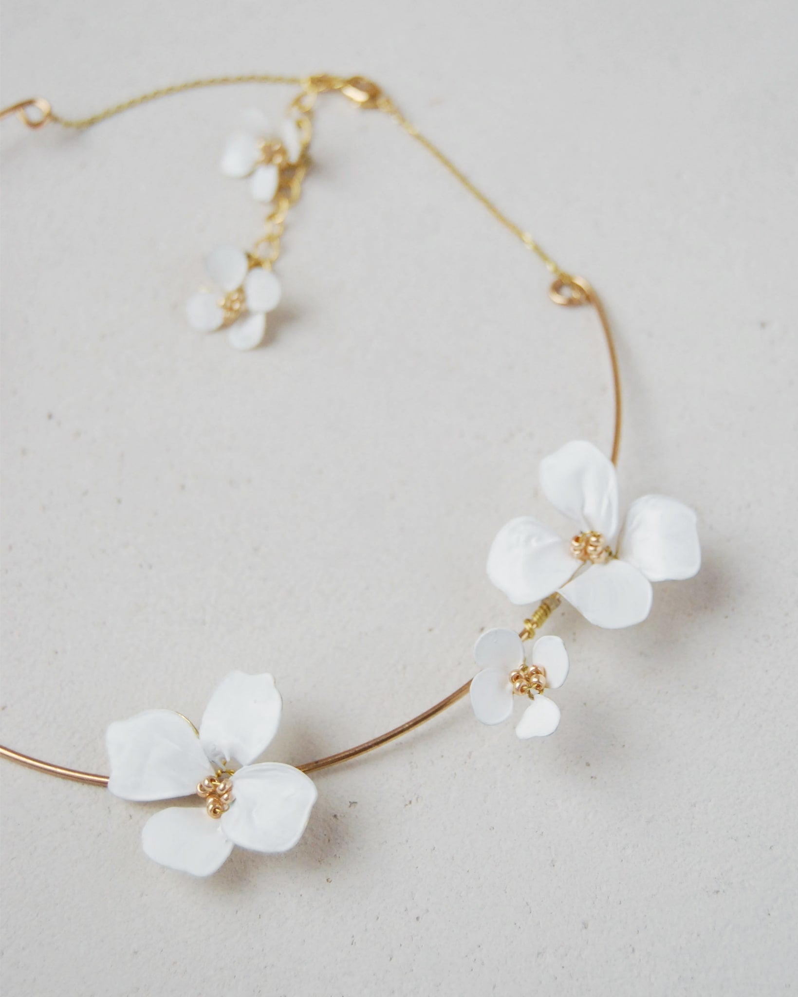 Collana rigida con fiori bianchi, accessorio unico e delicato, perfetto per il matrimonio e per aggiungere eleganza al look da sposa.