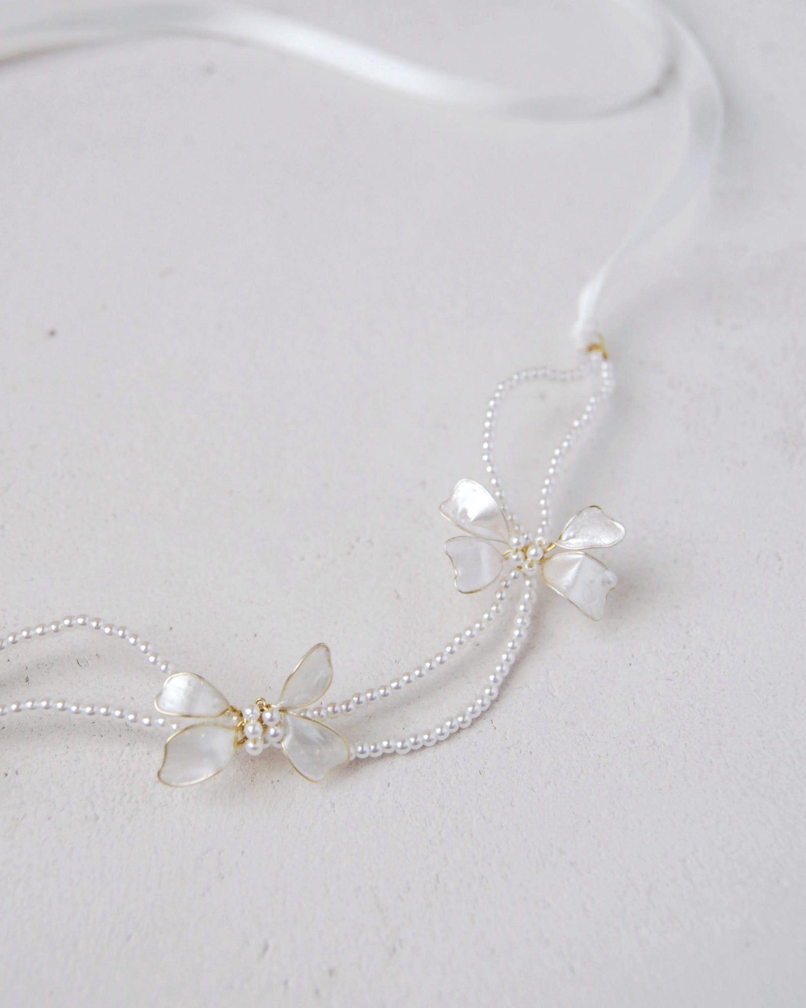 Coroncina decorata con perline e fiocchi madreperlati, ideale per matrimoni eleganti.