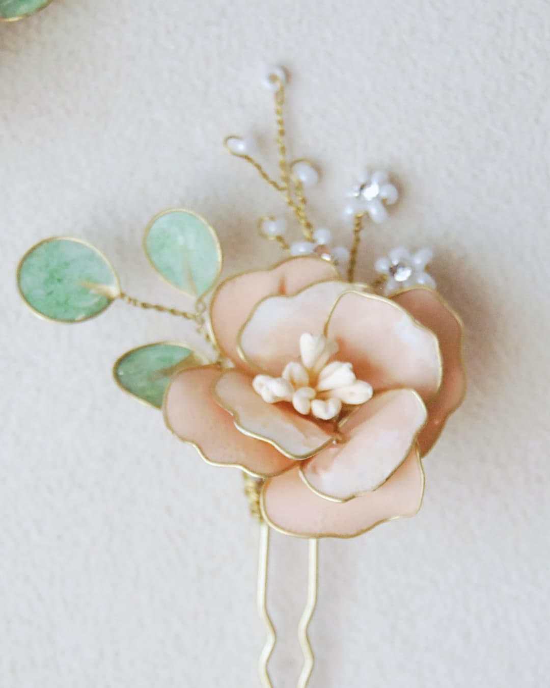 Dettaglio delle foglie di eucalipto artigianali e ramificazioni di perle nelle forcine Peonia Albarosa.