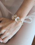 Dettaglio del bracciale Sakura indossato al polso, con petali sfumati e finiture dorate per un look nuziale poetico.