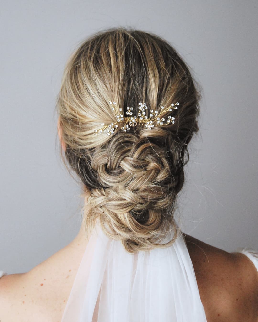 Primo piano dei fiori di cristallo e delle perle naturali del pettinino Brillaflora su indosso con velo da sposa