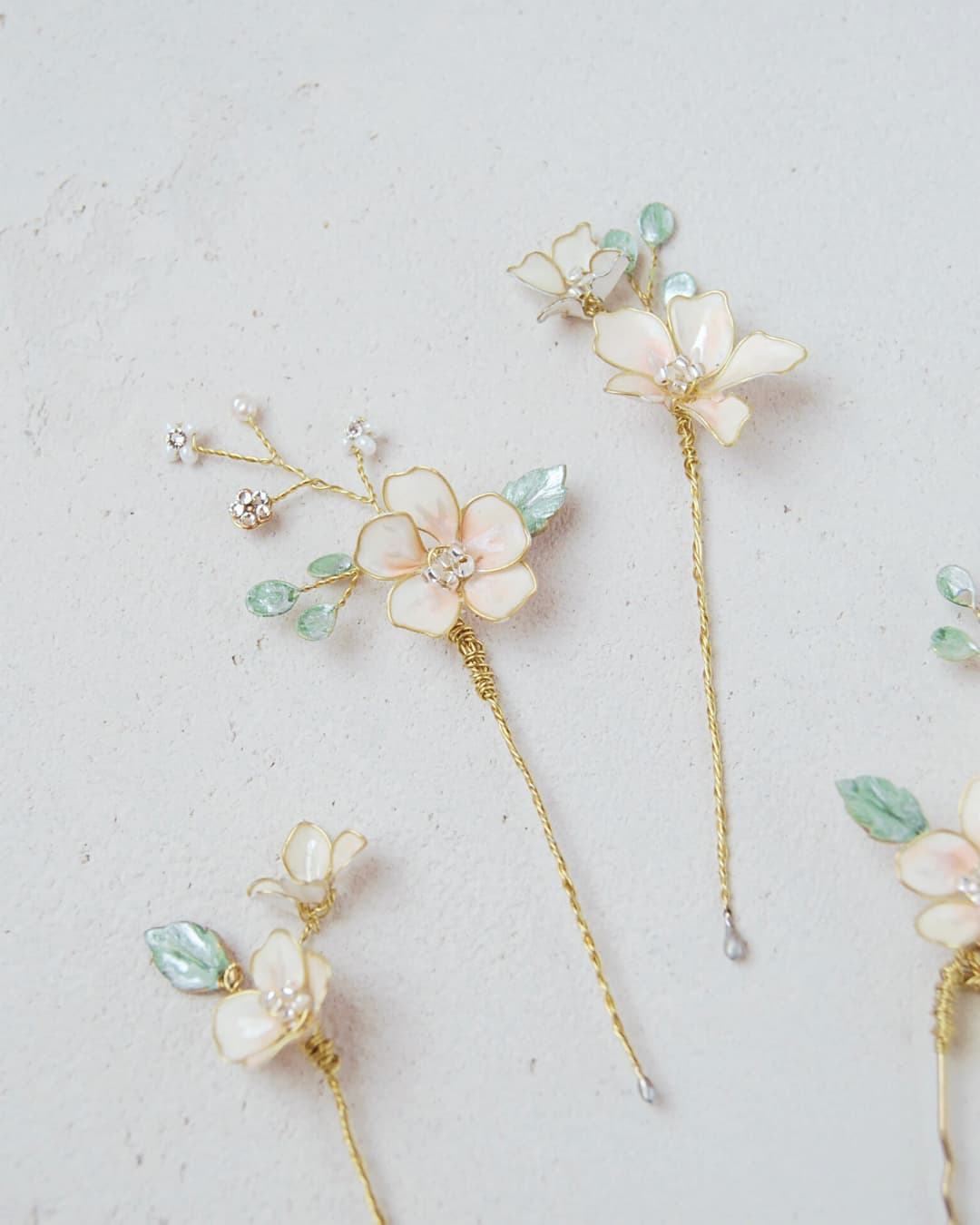 Particolare ravvicinato delle foglie in resina verde effetto vetro e fiori madreperlati con finitura dorata.