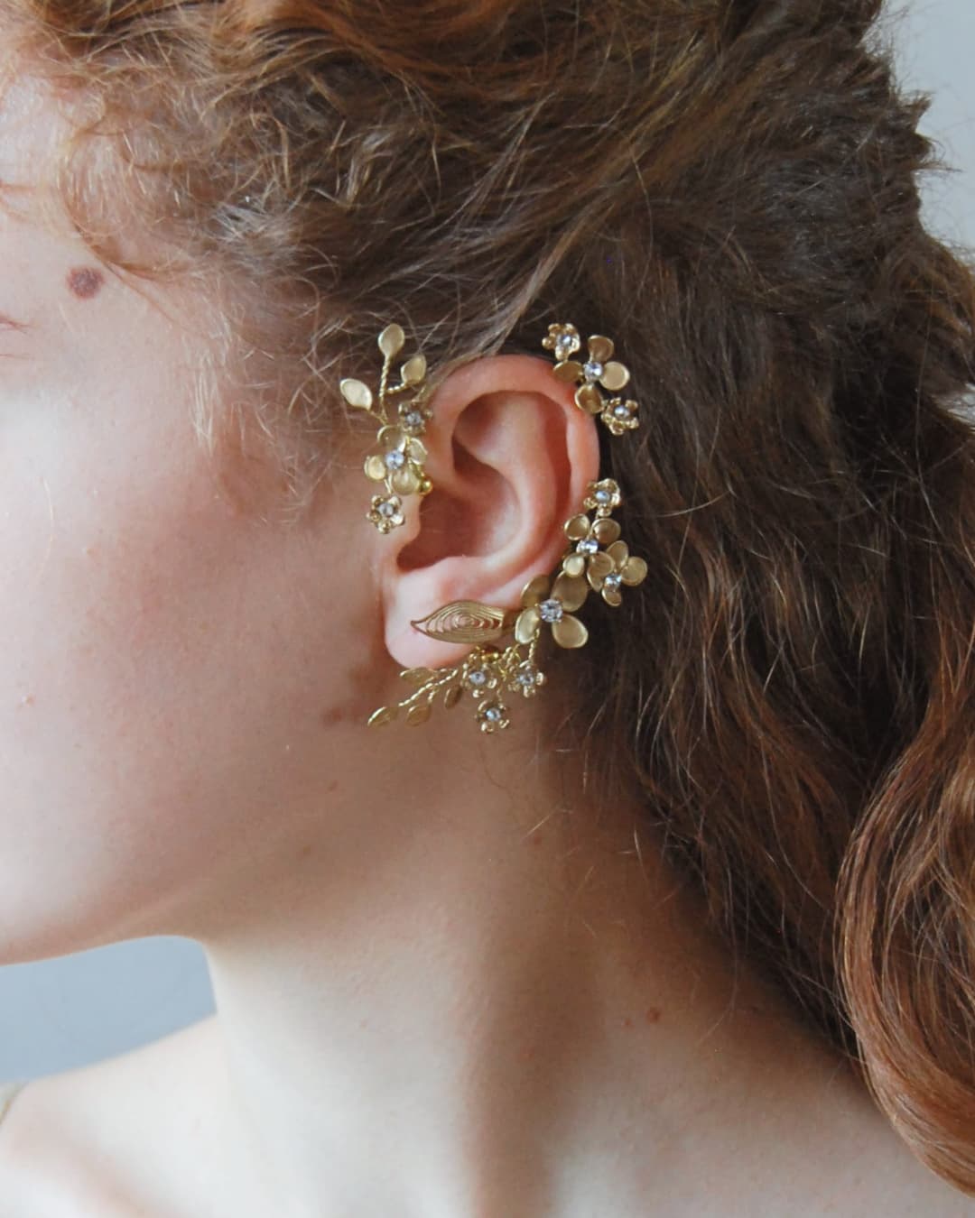 Ear cuff Aurum Elibre: un gioiello scultoreo in oro che avvolge l'orecchio con un design unico per una sposa d'élite.