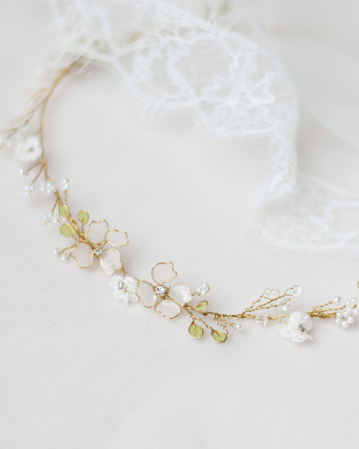 Coroncina Floralis da sposa con fiori bianchi in pizzo e rametti verdi, romantica e boho chic, modellabile e versatile per raccolti o capelli sciolti.