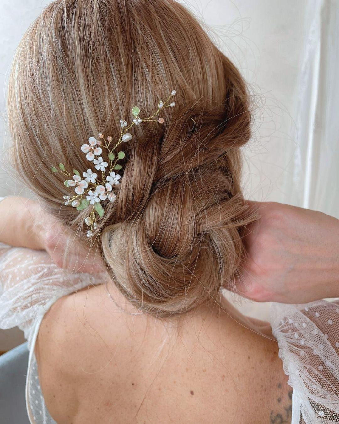 Dettaglio delle foglie verde salvia e dei fiori avorio della forcina a ramo Ramilla per cerimonie.